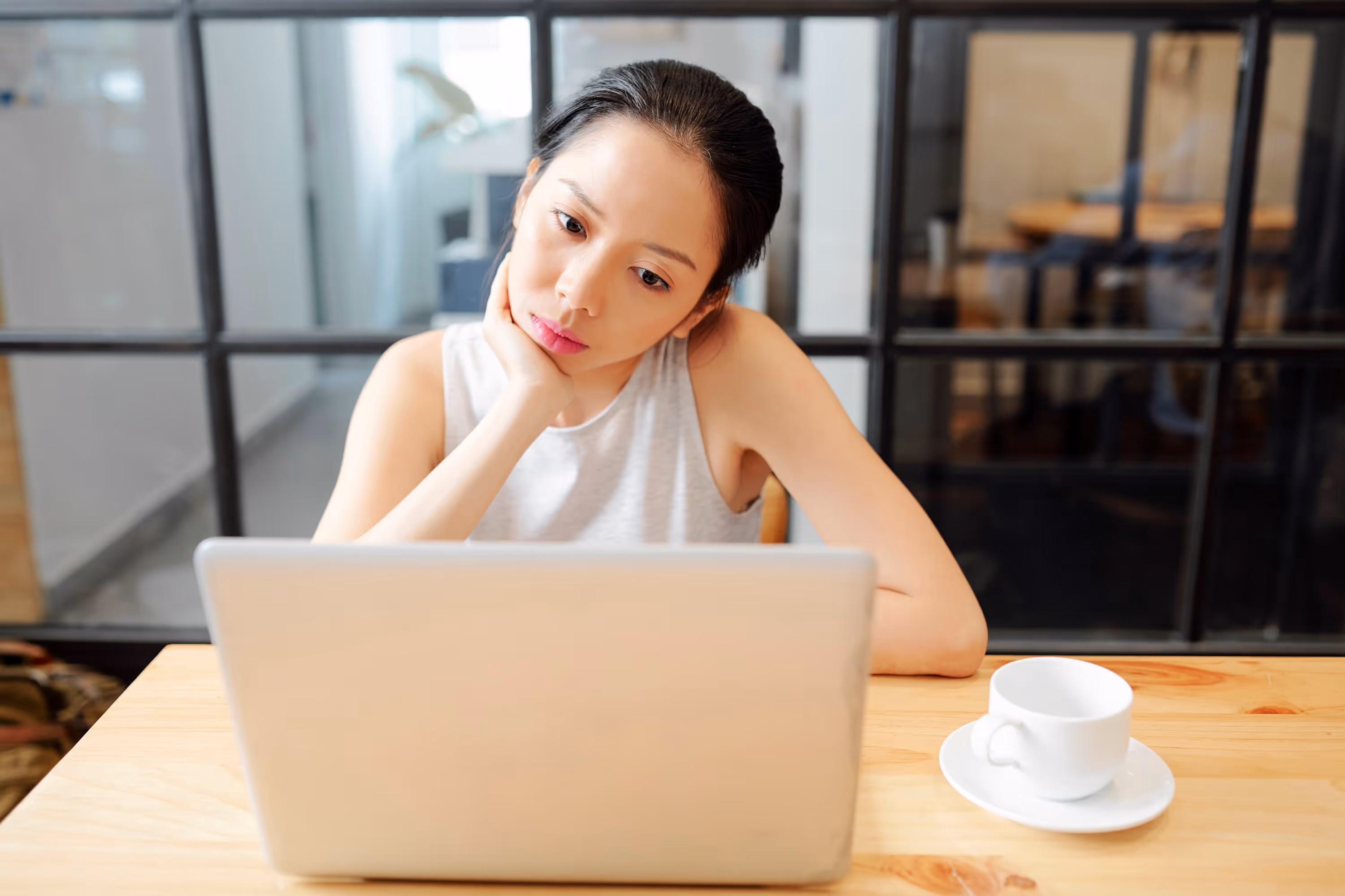 Woman looking thoughtfully at laptop