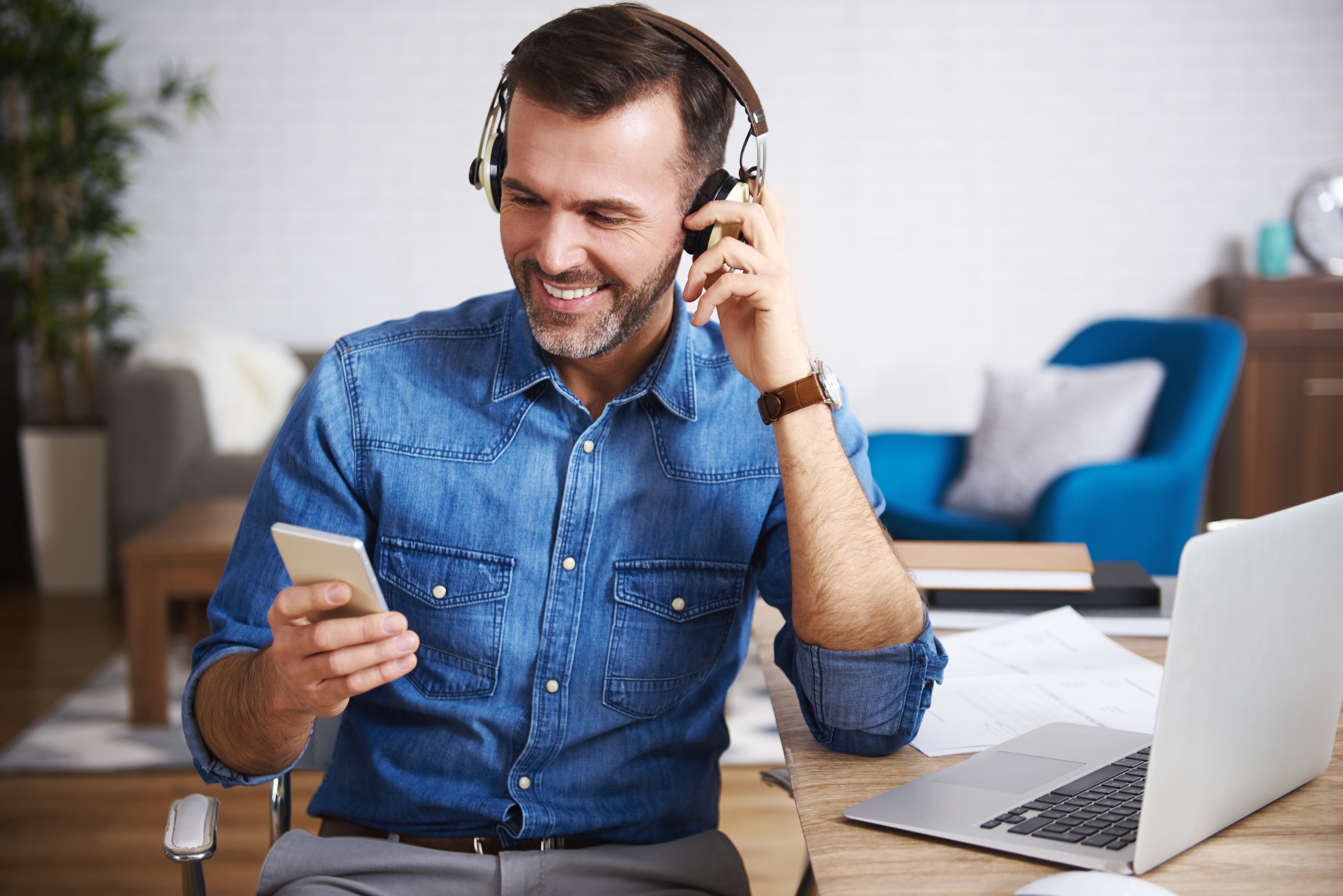 Man wearing headphones smiling looking at his phone