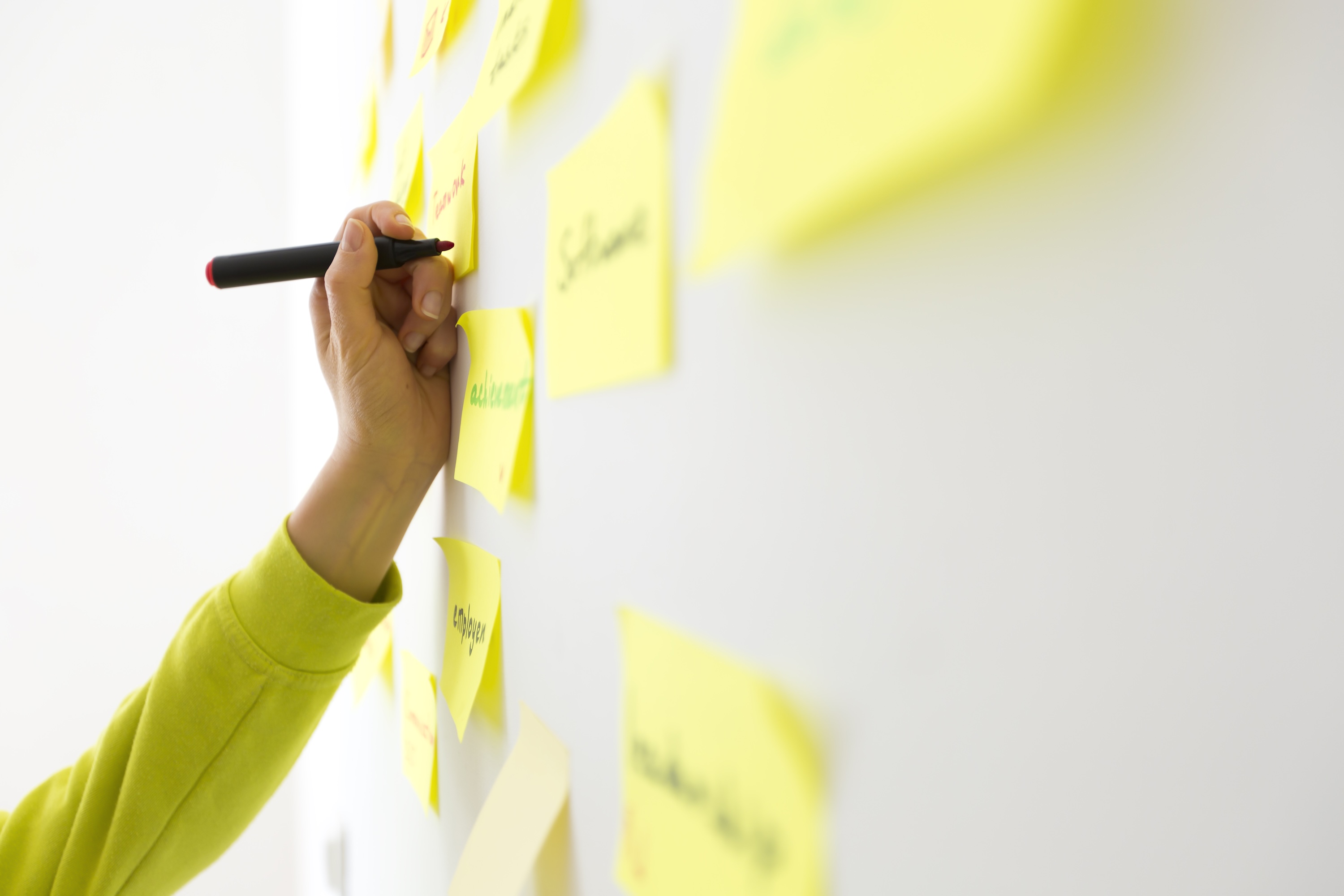 Person writing down ideas on Post-It notes