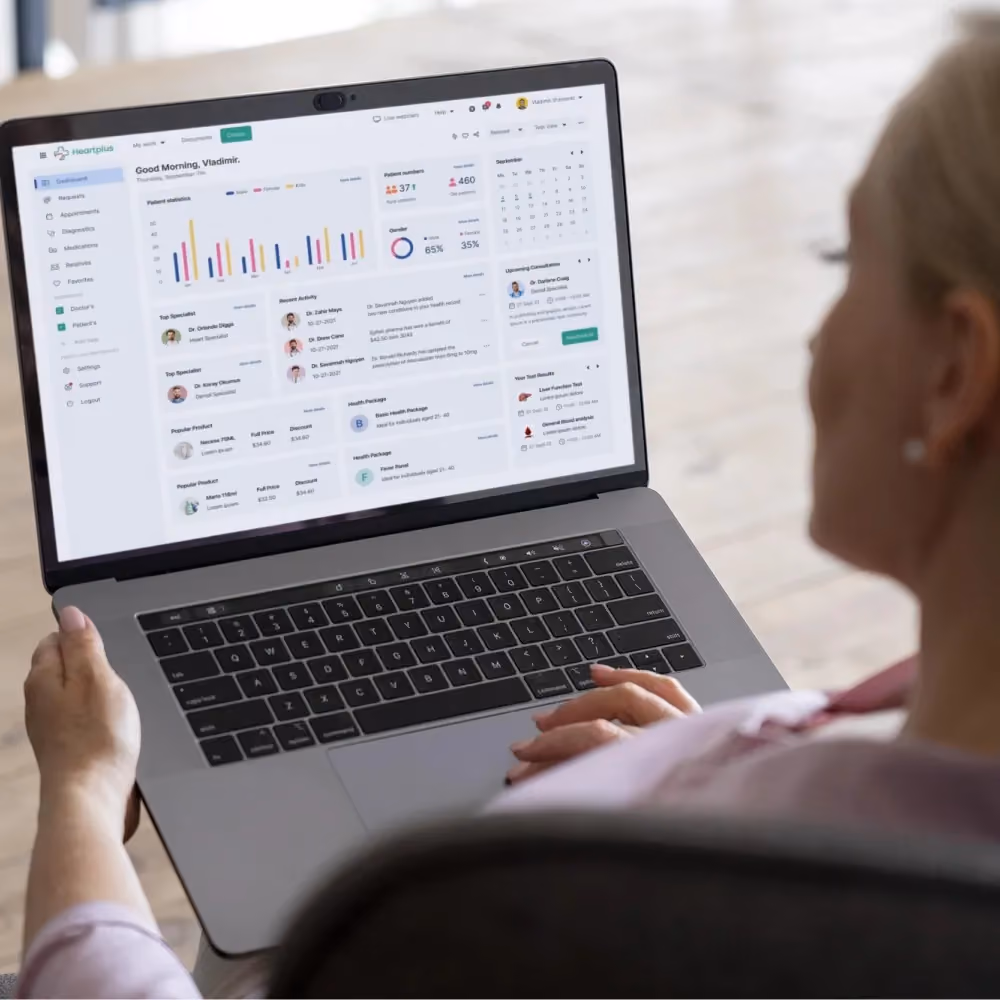A woman sits at a laptop displaying a graph, representing secure online booking for genetic tests.