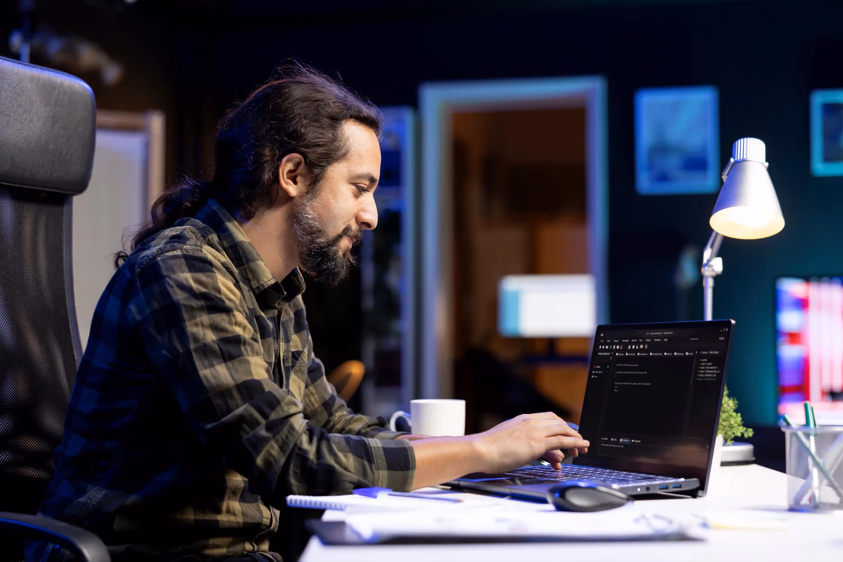 A man sits at a desk with a laptop, focused on scaling data generation using agentic AI systems in software development.