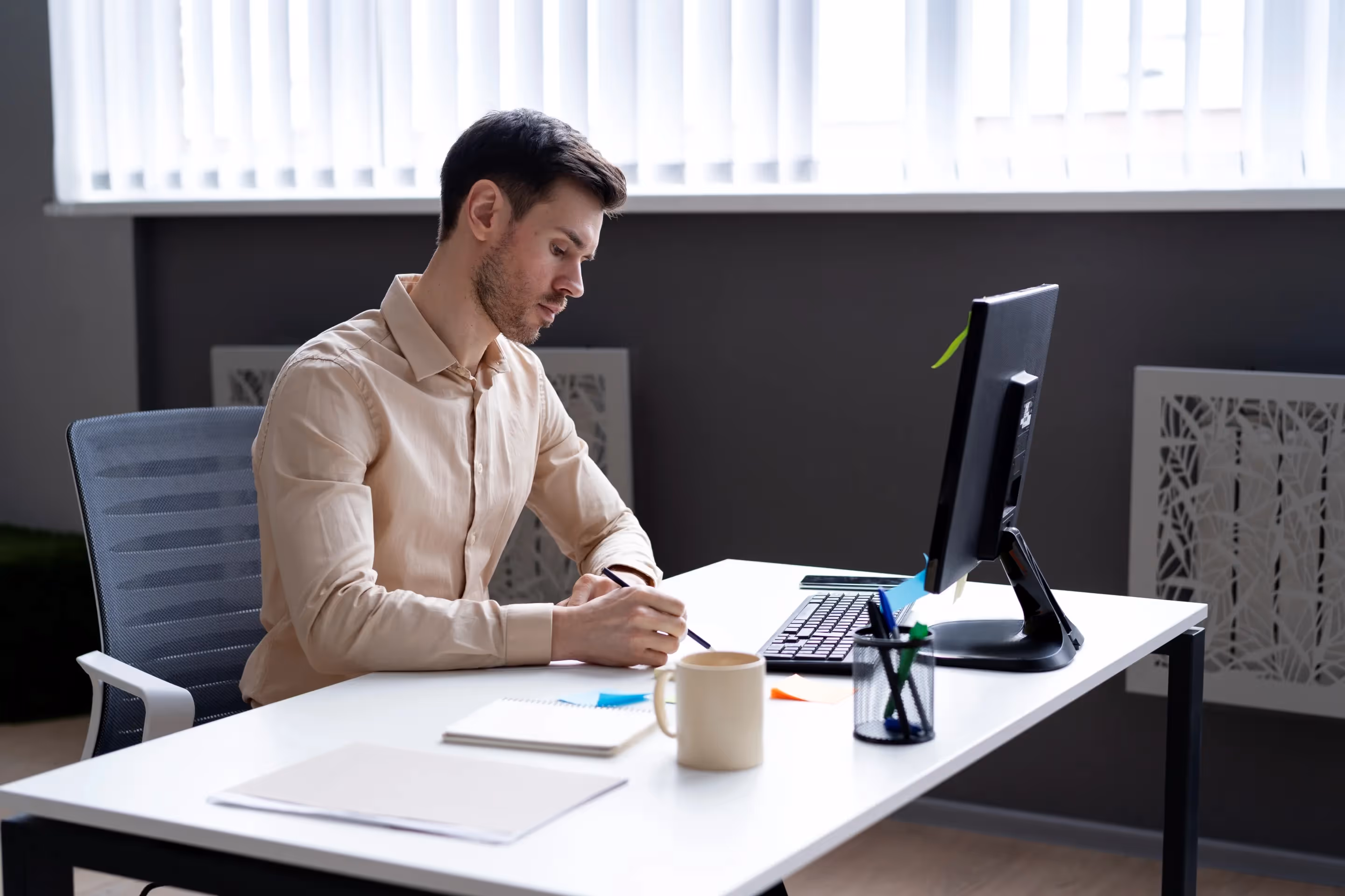 A man at a desk with a computer and pen, focused on transforming loan approval using AI and fractional CTO leadership.