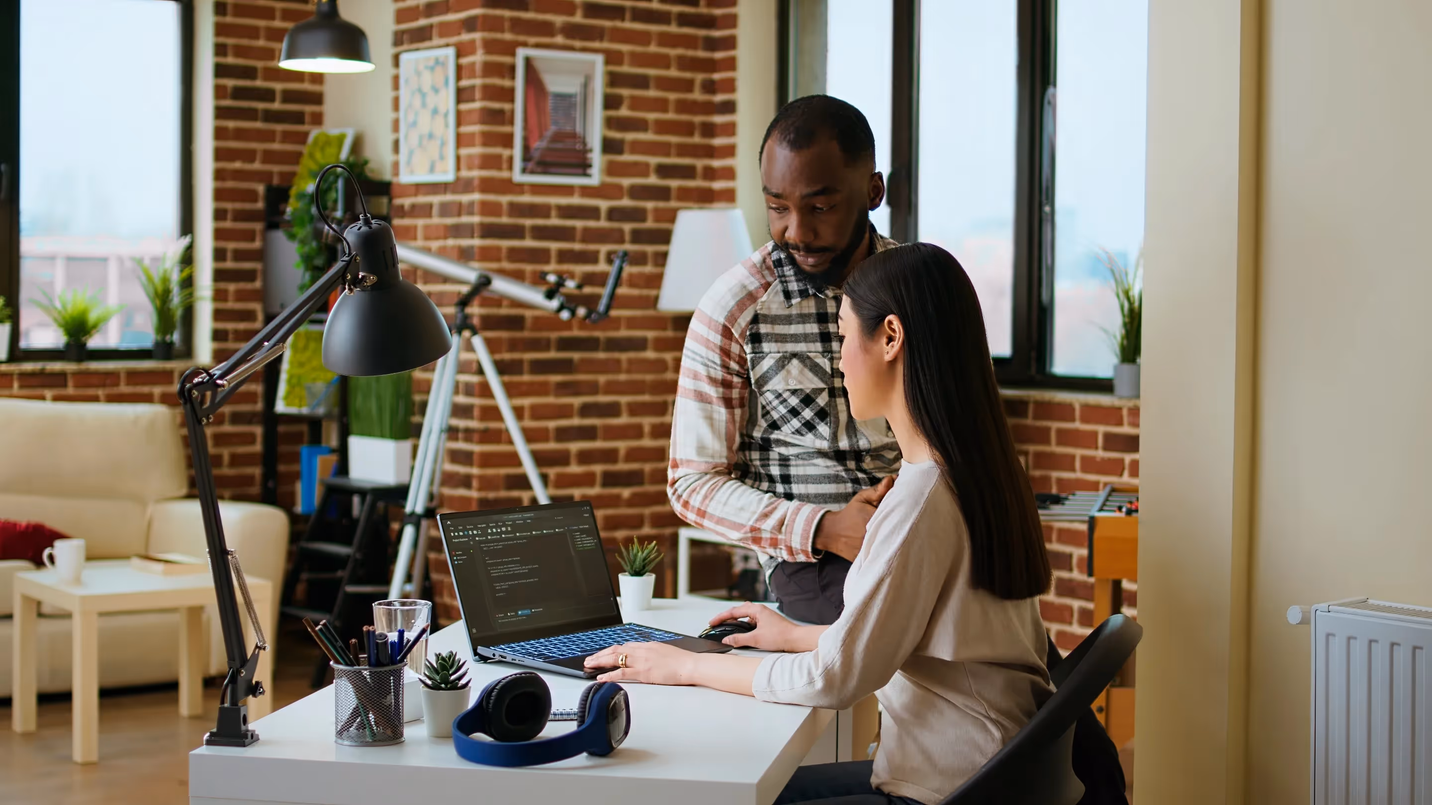 A man and woman collaborate on a laptop in an office, focusing on optimizing equipment management with advanced data handling.