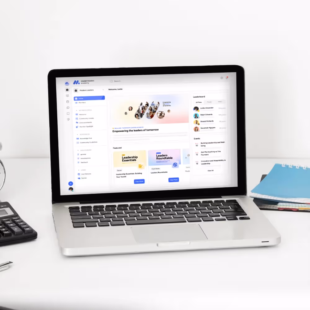 Laptop displaying a modern AI-powered training dashboard on a clean white desk with a calculator and notebooks nearby.