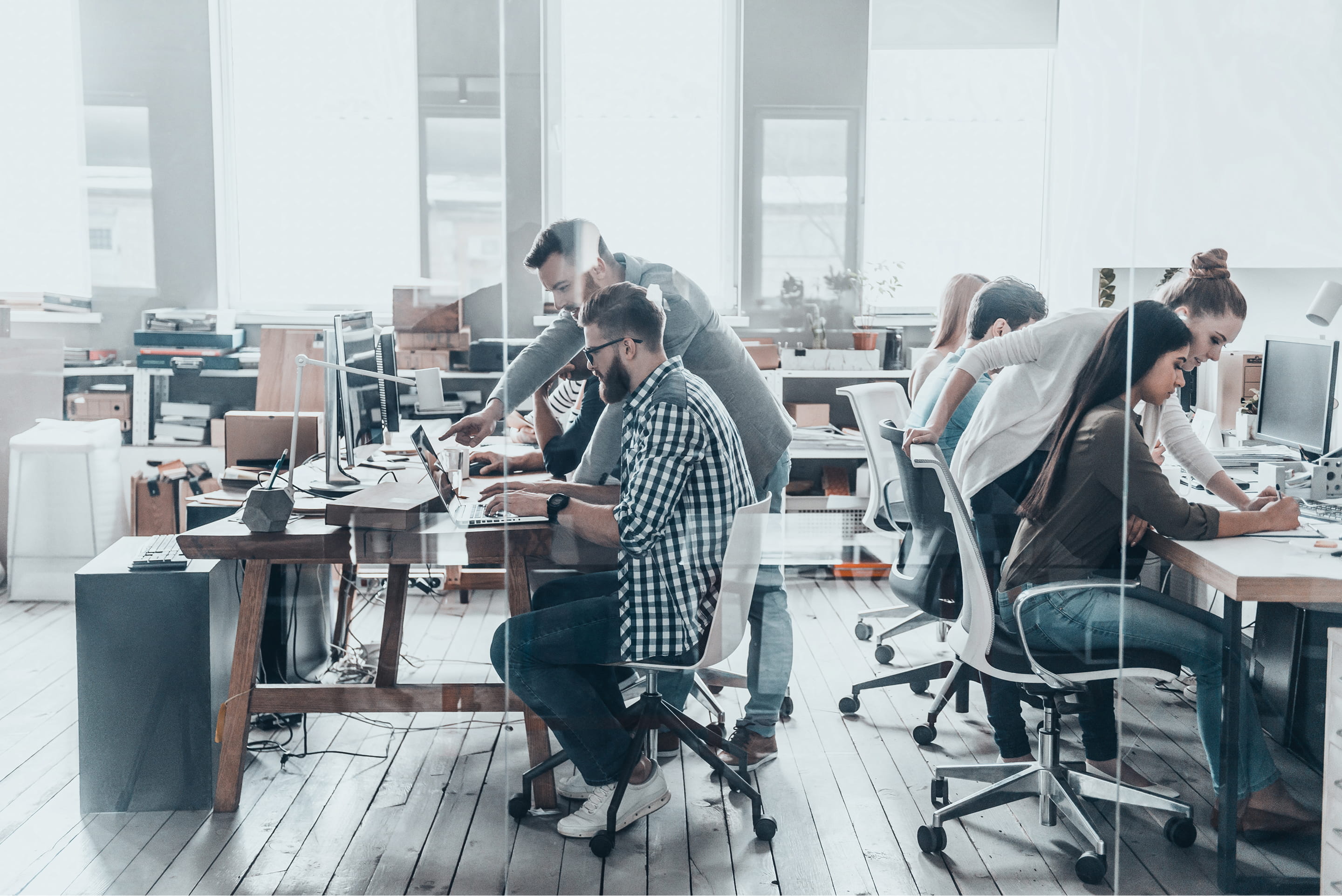 A diverse group of professionals collaborating at desks in a modern office environment.