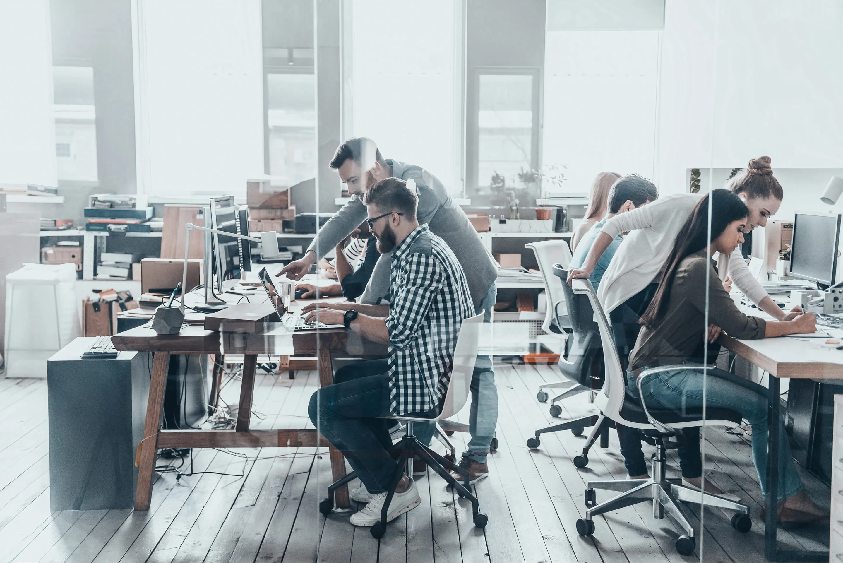 A diverse group of professionals collaborating at desks in a modern office environment.