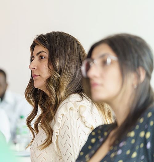 Close up of two people listening to someone speak