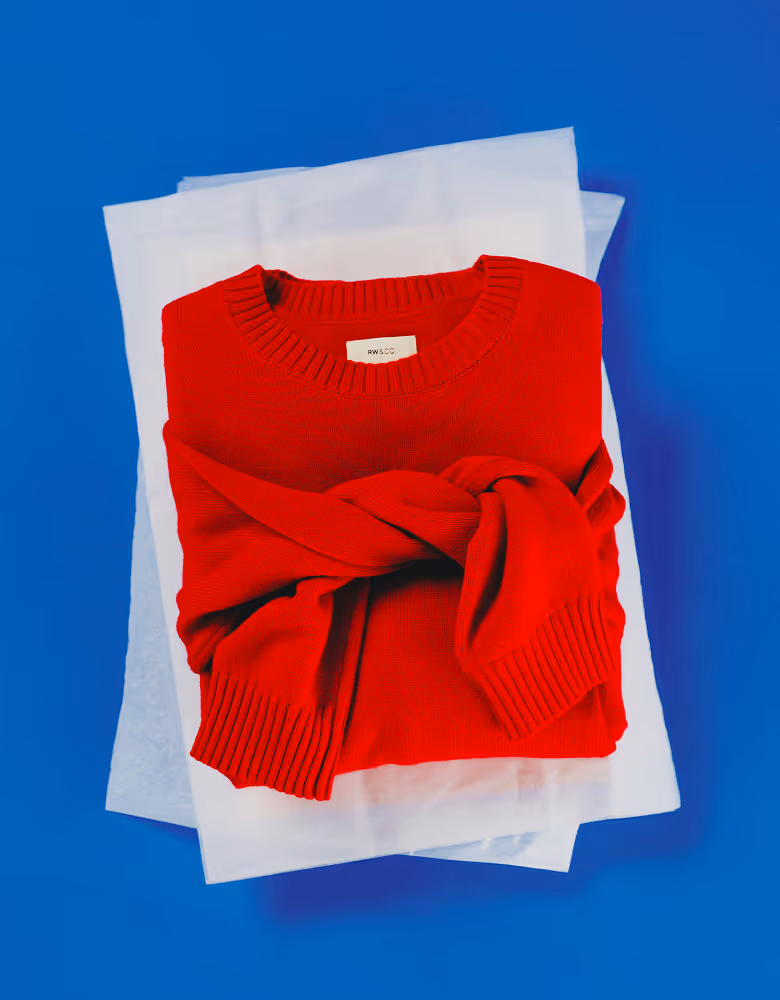 RW&Co Holiday 2025 Campaign Gift Guide Red sweater placed on white wrapping paper