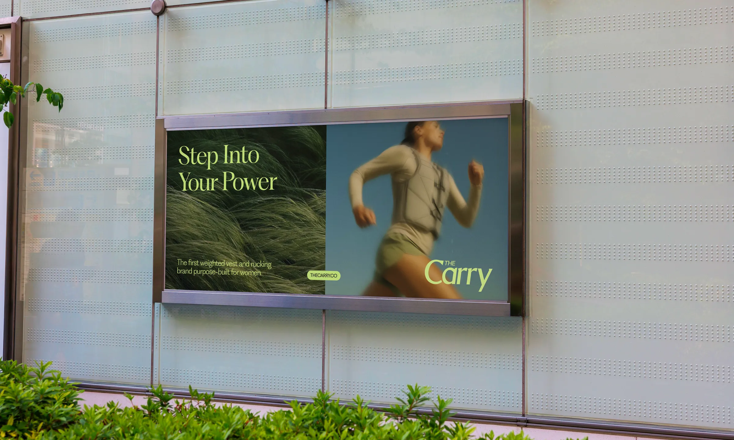 Billboard advertisement showing a woman running wearing a weighted vest, with text 'Step Into Your Power' and 'The Carry' brand logo on a glass wall.