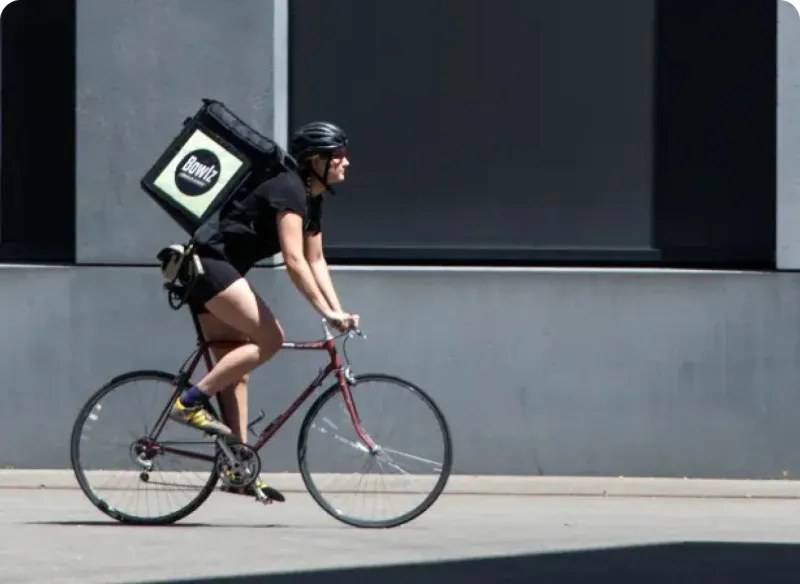 A Bowlz bike courier riding with an insulated delivery backpack