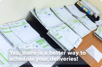 A desk covered with piles of printed delivery notes, hand-sorted and ordered to create delivery routes. Overlay text says “Yes, there is a better way to schedule your deliveries!”