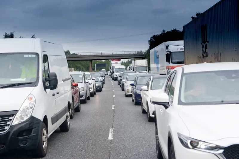 Alt: Cars and trucks stuck in bumper-to-bumper traffic on a highway.