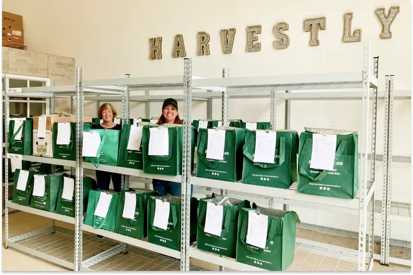 Workers at Harvestly pose in their storeroom with a selection of totes packed and ready to deliver.
