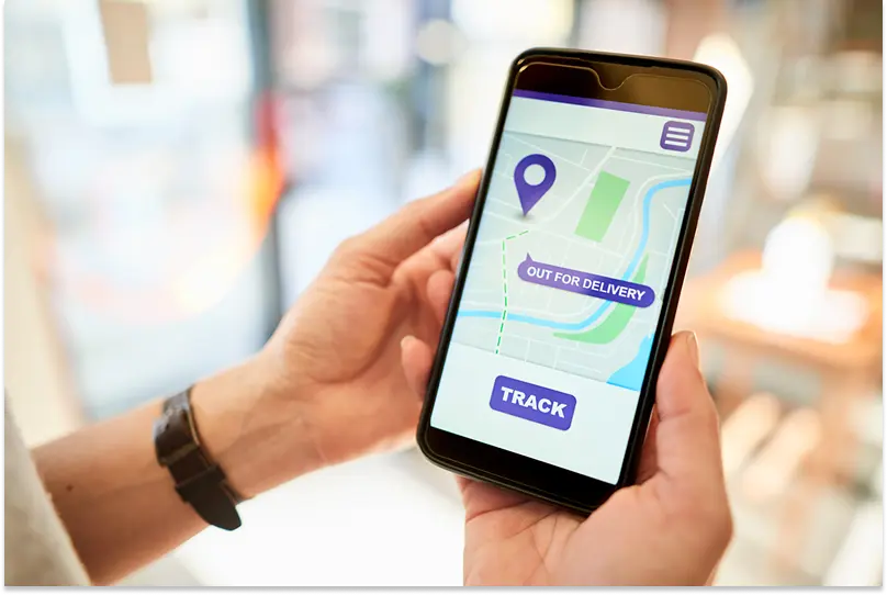 A person is holding a mobile phone showing a map with a live delivery tracking link.