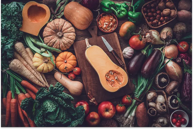 A table full of fall seasonal vegetables like squash, aubergines and cabbages.