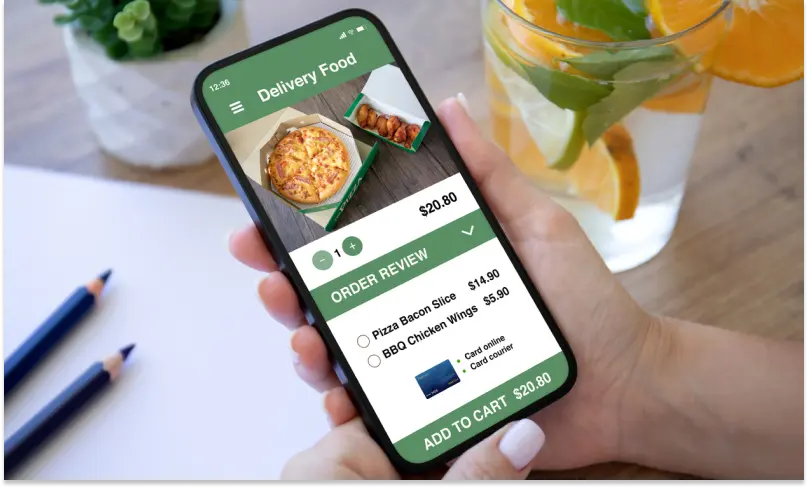 View of a mobile phone held in a woman’s hands. The screen shows an online food order in progress.