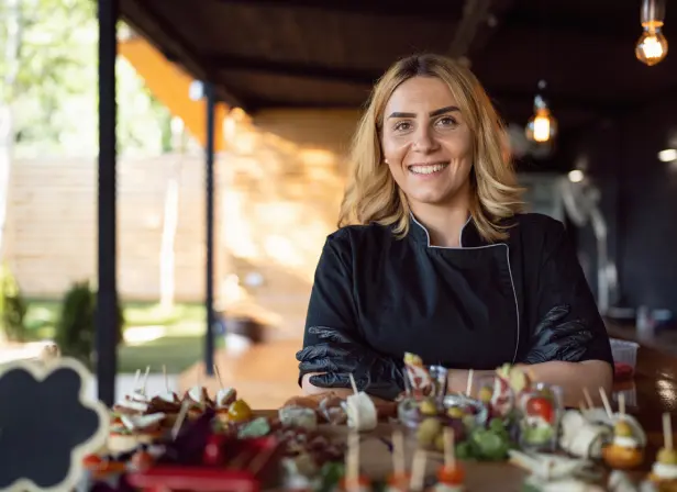 A young woman in a catering uniform stands with trays of canapes