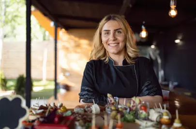 A young woman in a catering uniform stands with trays of canapes