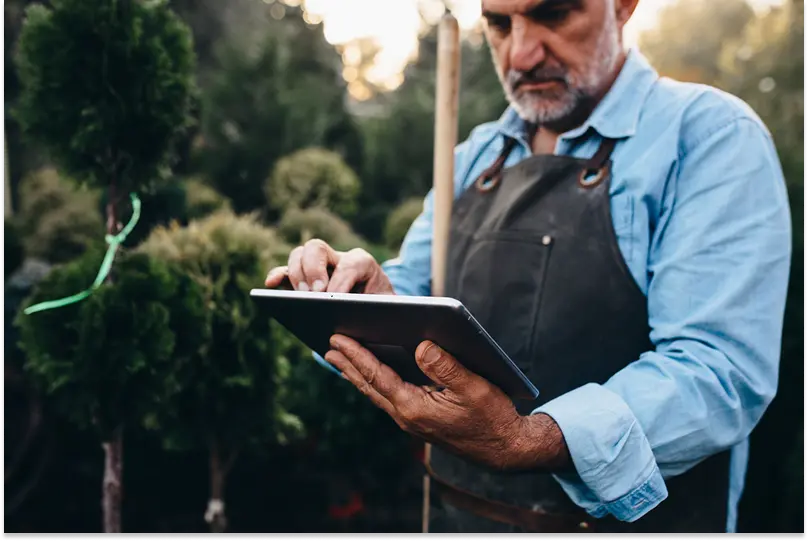 A landscaping business owner uses a tablet to calculate pricing for a job.