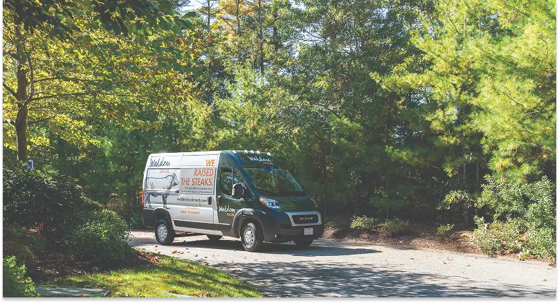 A Walden-branded delivery van on a tree-lined driveway