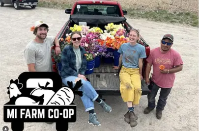 Four co-op members pose with their truck loaded with fresh flowers ready for delivery.