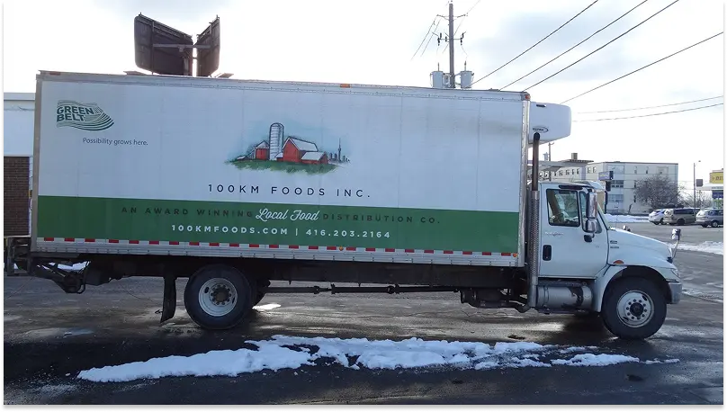 A 100km Foods truck pictured on a snowy Ontario street.