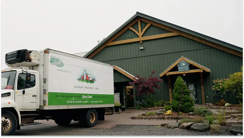 A 100km Foods delivery truck parked in front of Nest restaurant. 
