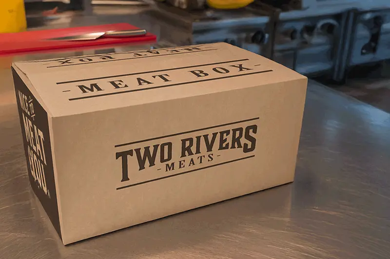 A cardboard delivery boxed with Two Rivers Meats branding.