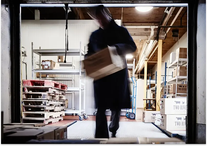 A warehouse worker at Two Rivers Specialty Meats loads boxes into a truck for delivery.