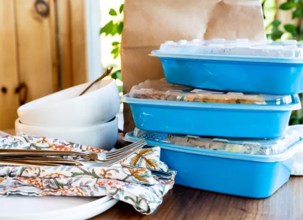 Three Red Apron meals packaged in blue reusable containers.