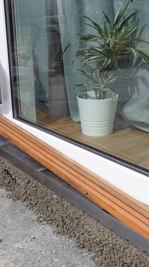 Eine Entwässerungsrinne wir vor einem Gartenfenster eineglassen.