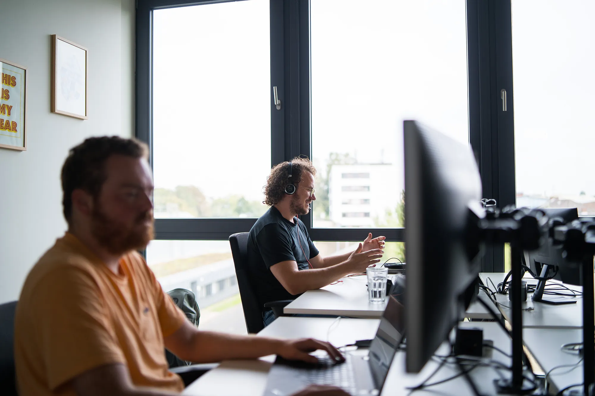 Zwei Mitarbeitende sitzen am Schreibtisch im Büro.