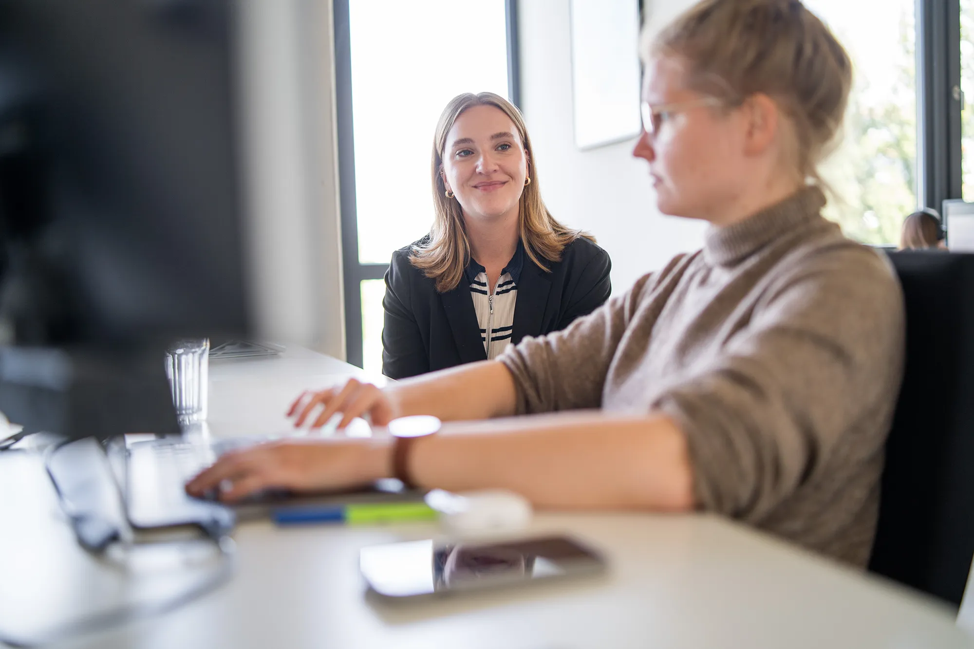 Zwei Mitarbeitende sitzen vor dem PC.