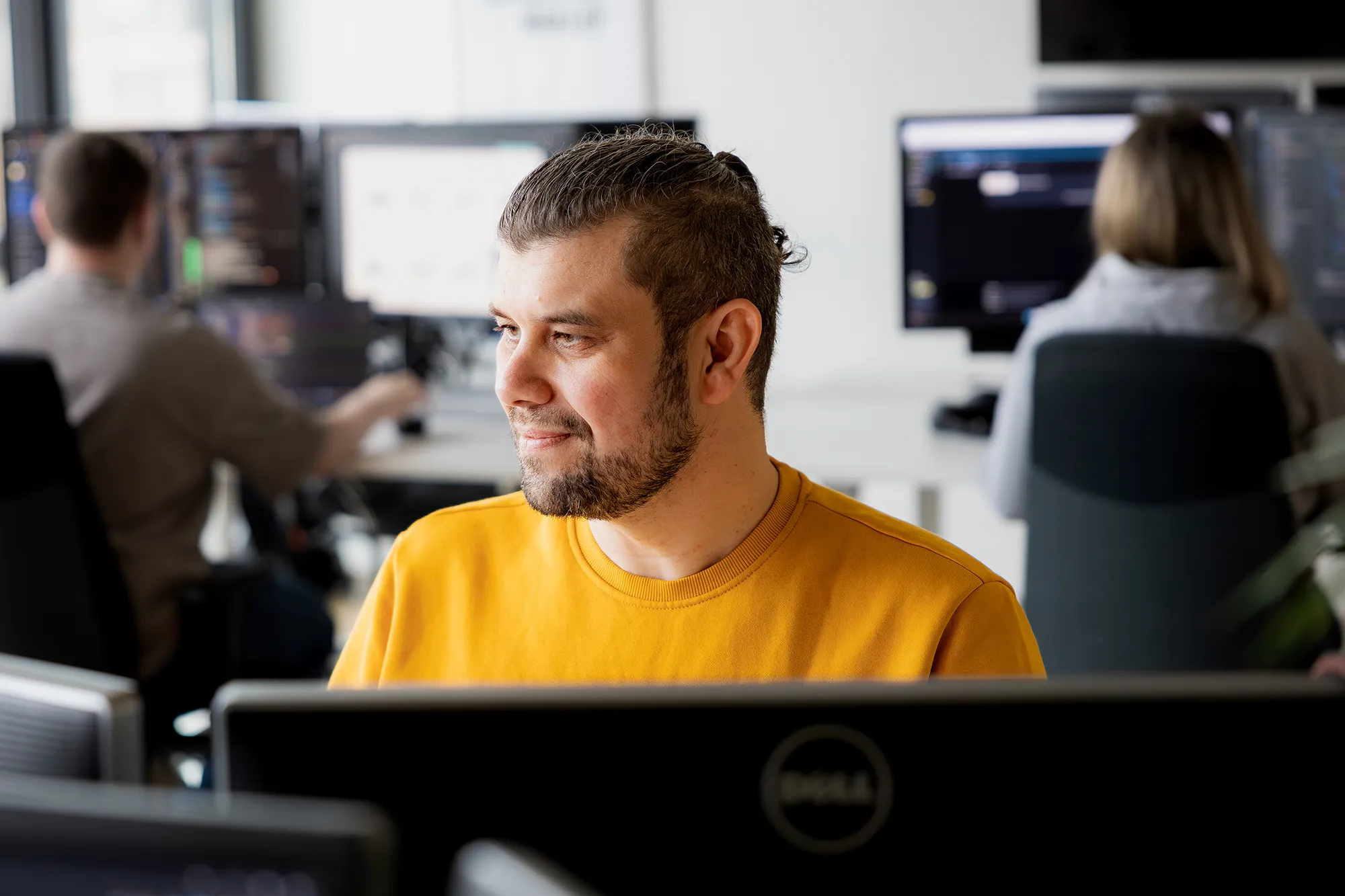 Mitarbeitender im Büro mit Kolleg*innen im Hintergrund