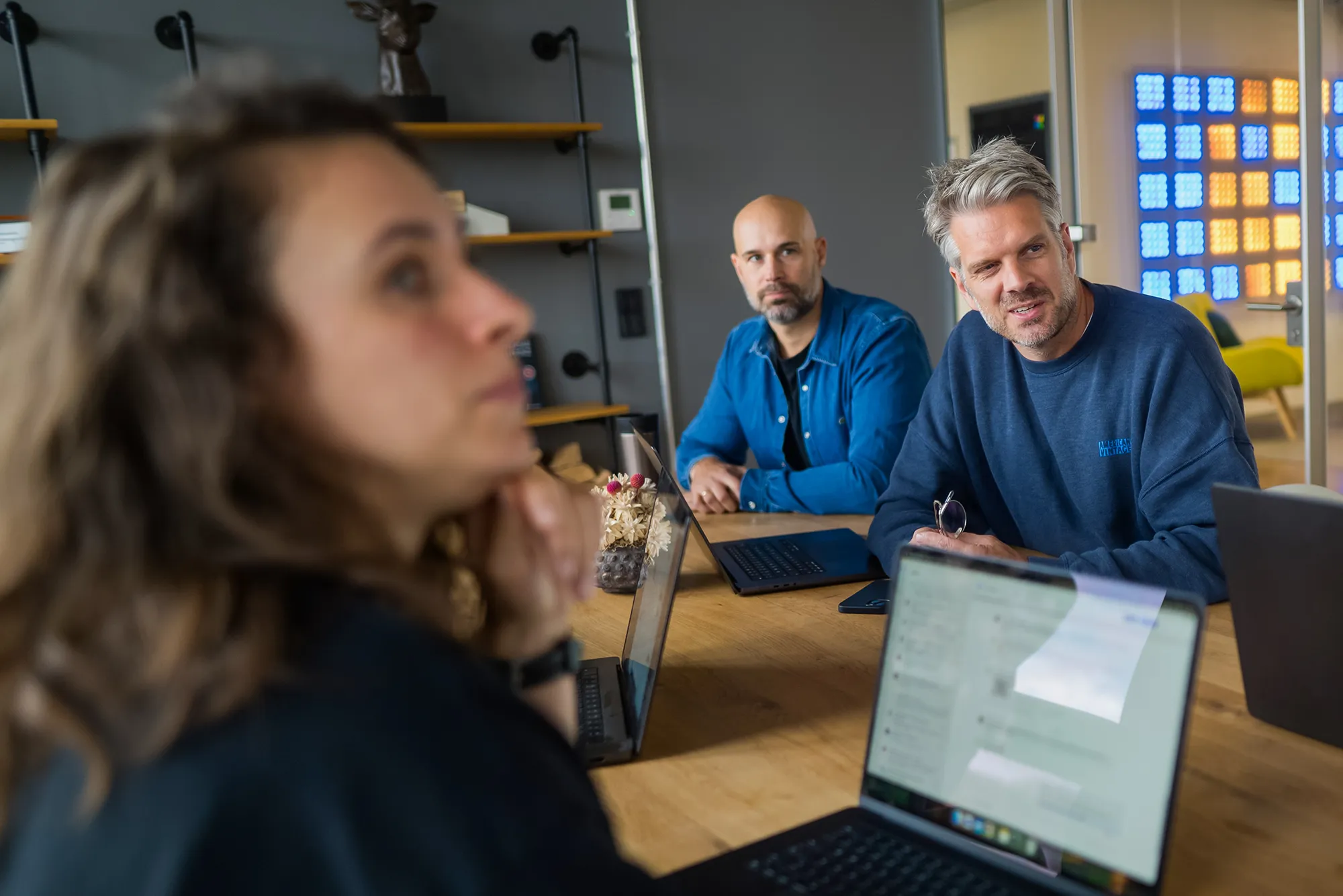 Drei Mitarbeitende schauen in Richtung Präsentation.