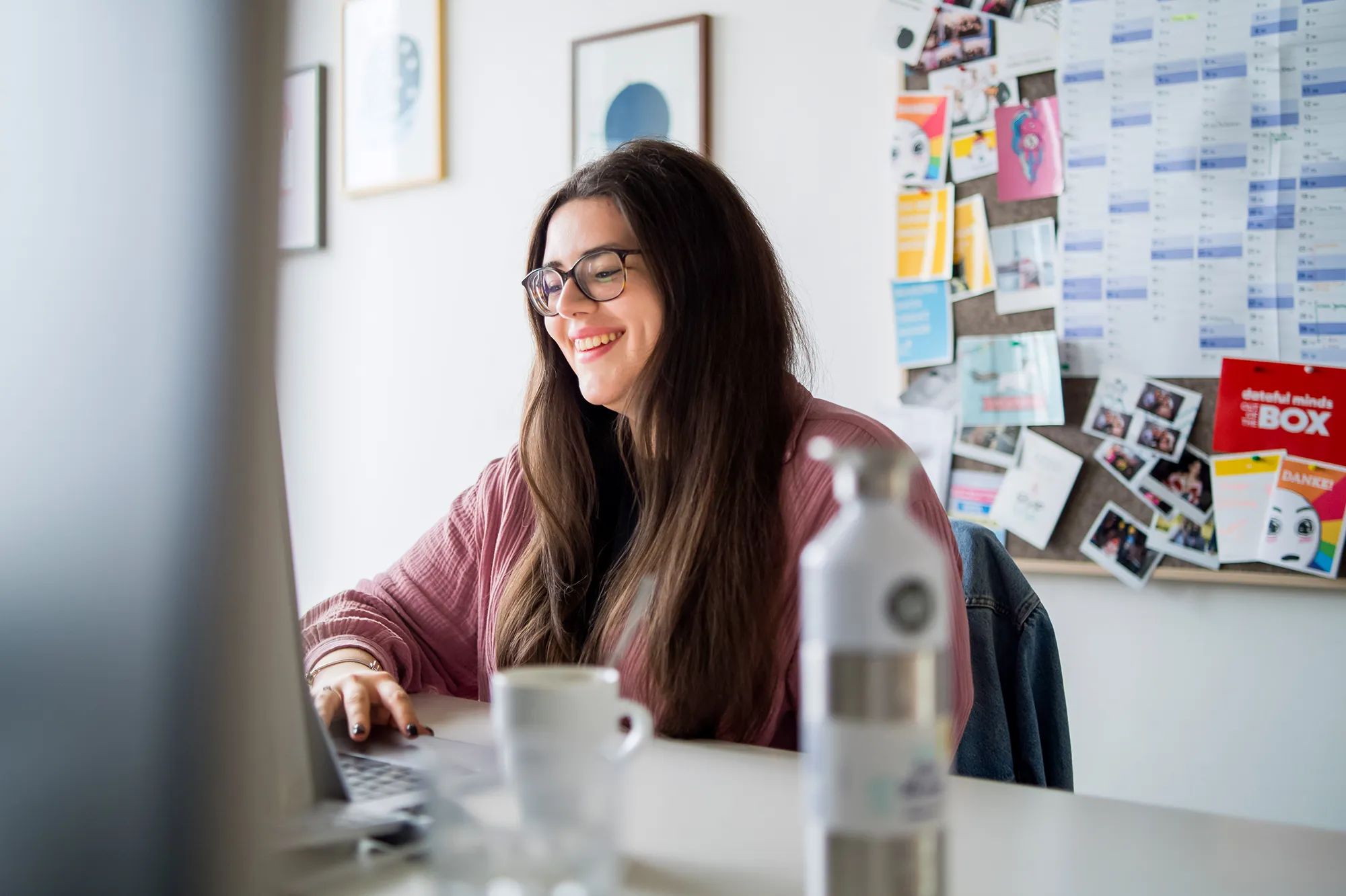 Mitarbeitende schaut freudig auf den Monitor.