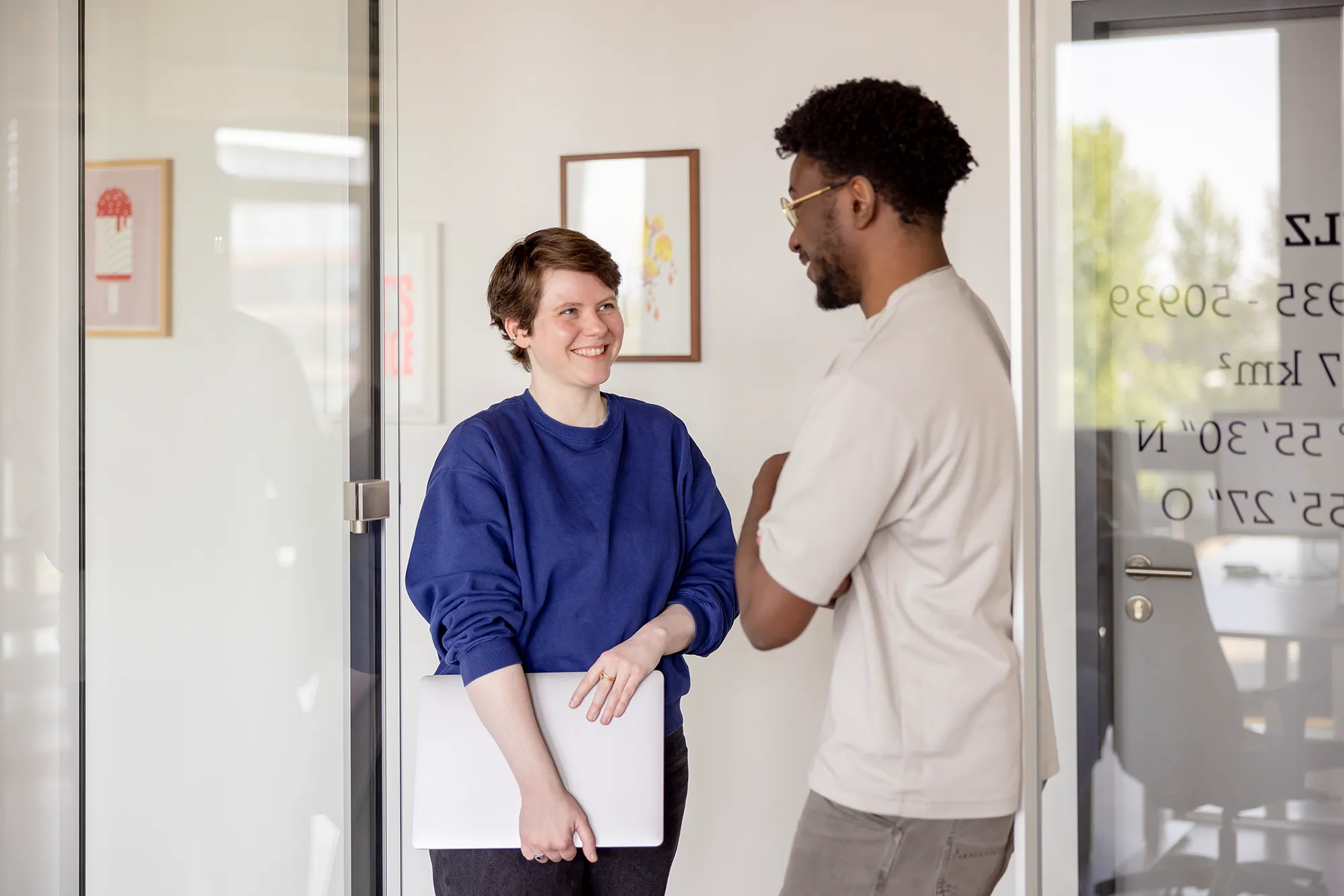 Zwei Mitarbeitende unterhalten sich in der Eingangstür zum Büro