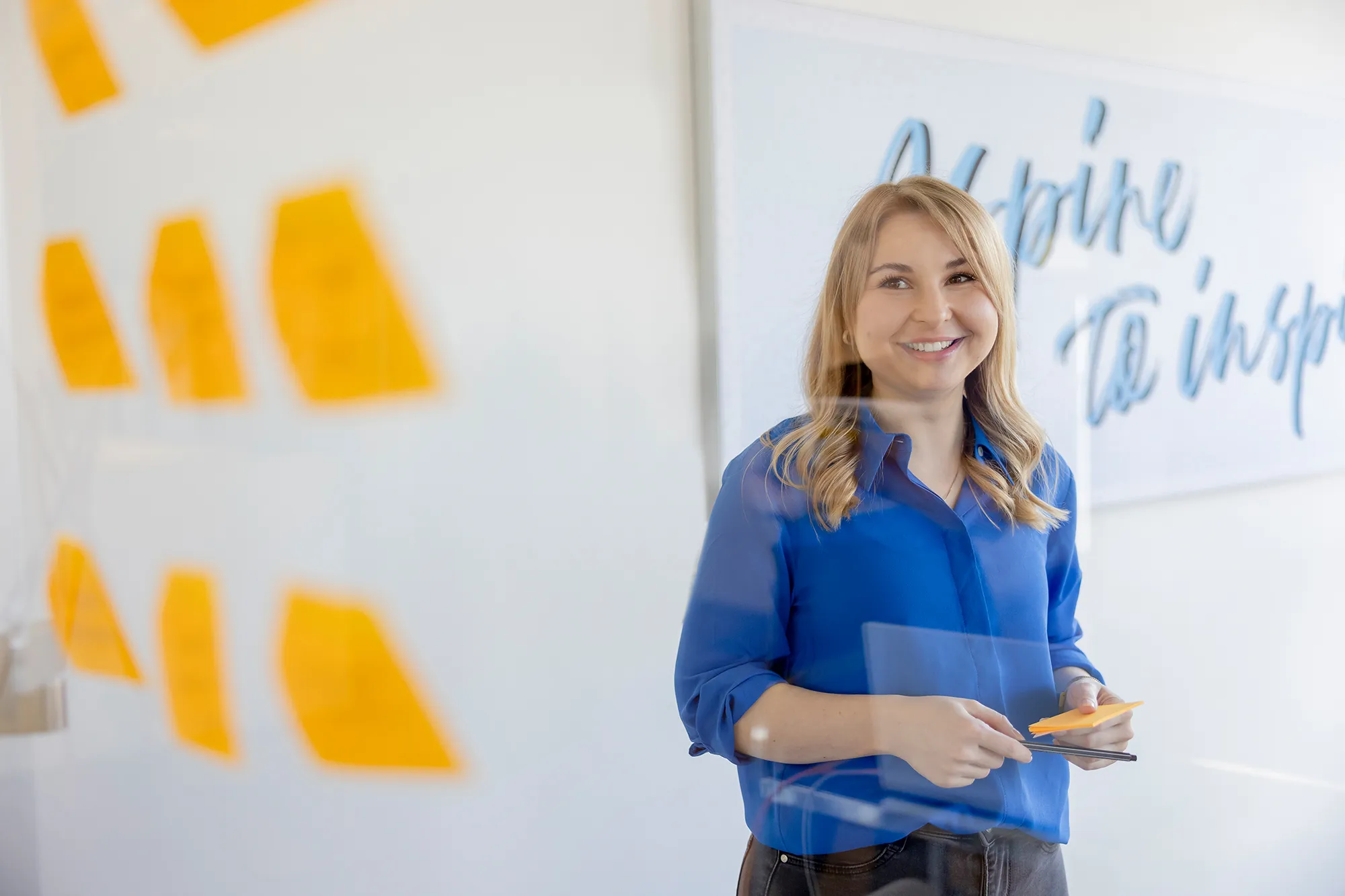 Mitarbeiterin pinnt Notizen an Glaswand