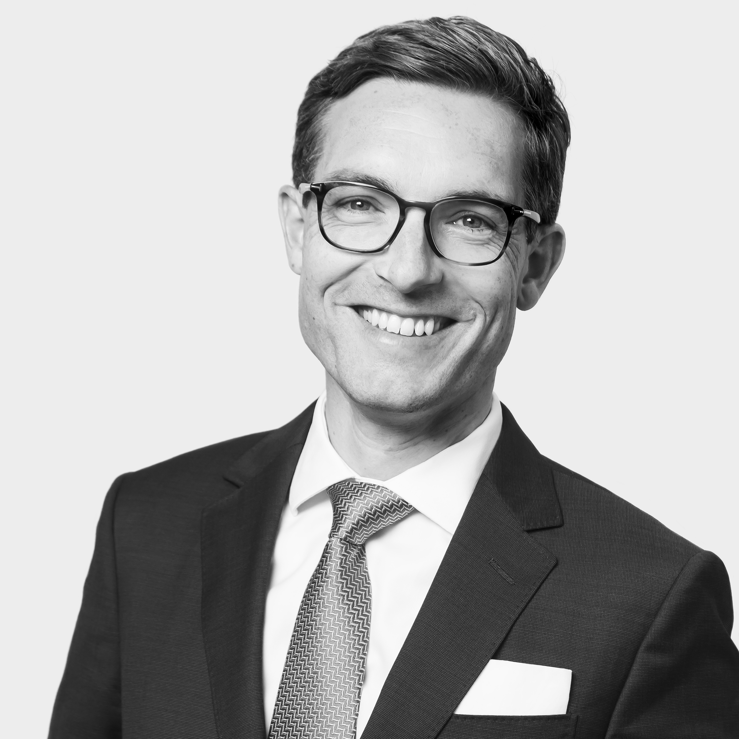 Dr. Daniel Kendziur, Rechtsanwalt und Partner bei SKW Schwarz, lächelnd in einem Schwarz-Weiß-Portrait.