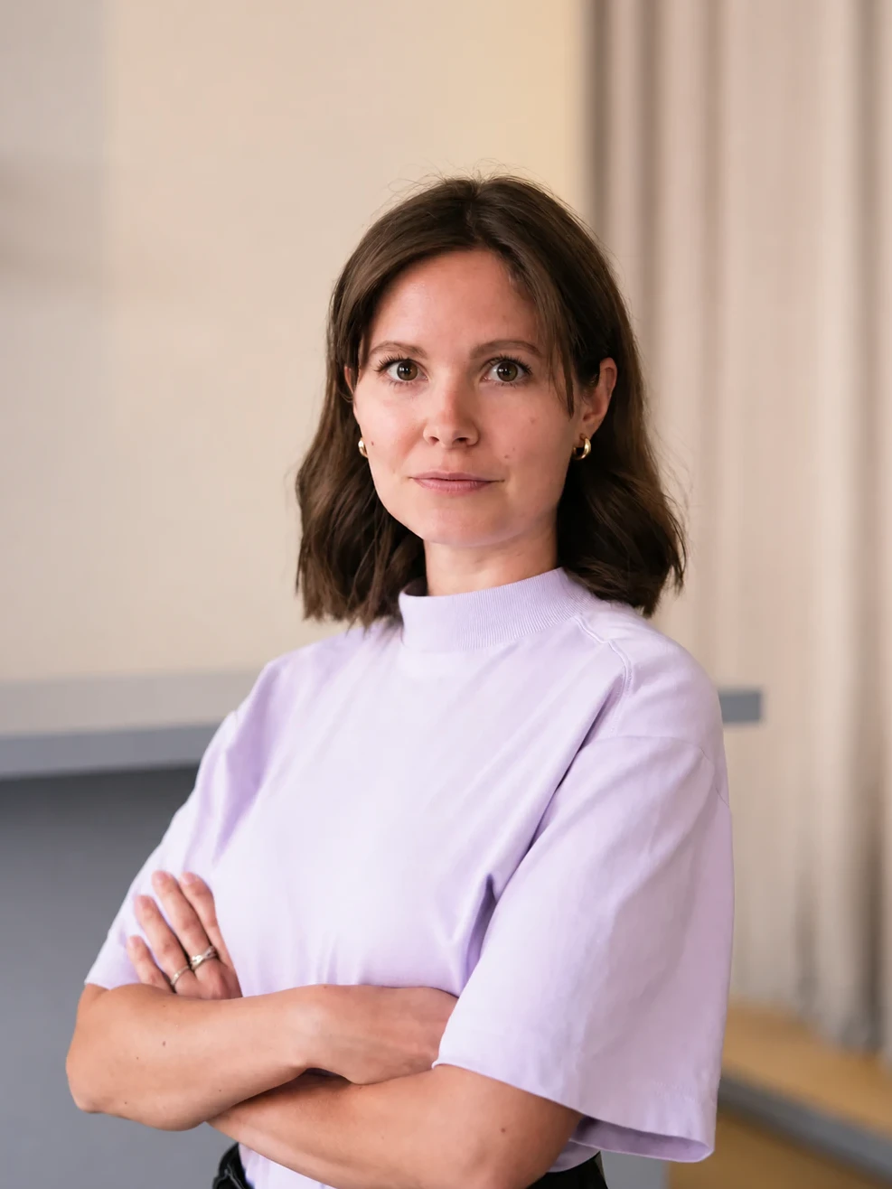 Liza Rüger, M. Eng. Innenarchitektur und Projektleiterin bei Studio ABERJA, mit verschränkten Armen in einem hellen Büro.