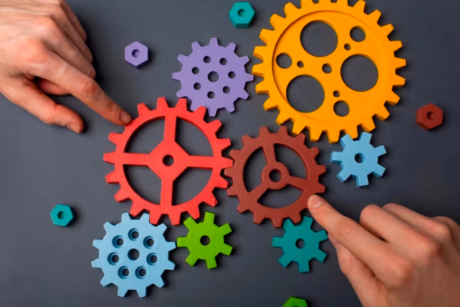 Image of cogs on a table with two hands moving the cogs, representing operational efficiency in insurance.