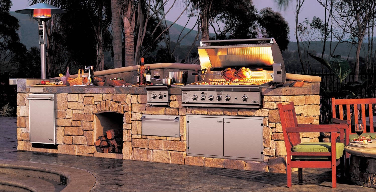 A rustic outdoor grill covered in stones in the patio of a house
