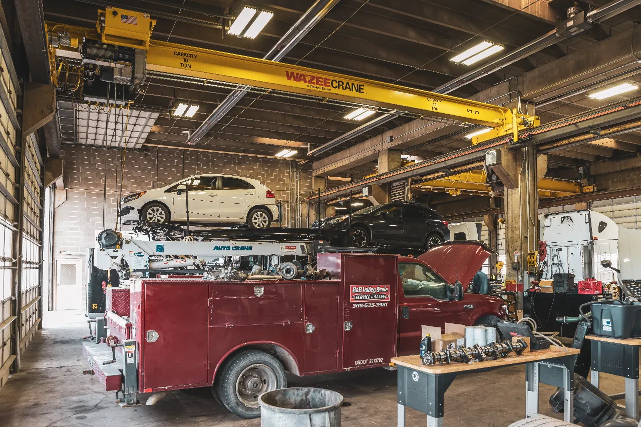 Diesel truck upfitting shop in Cheyenne, WY with service truck, lifted vehicles, and WAZEE CRANE overhead.