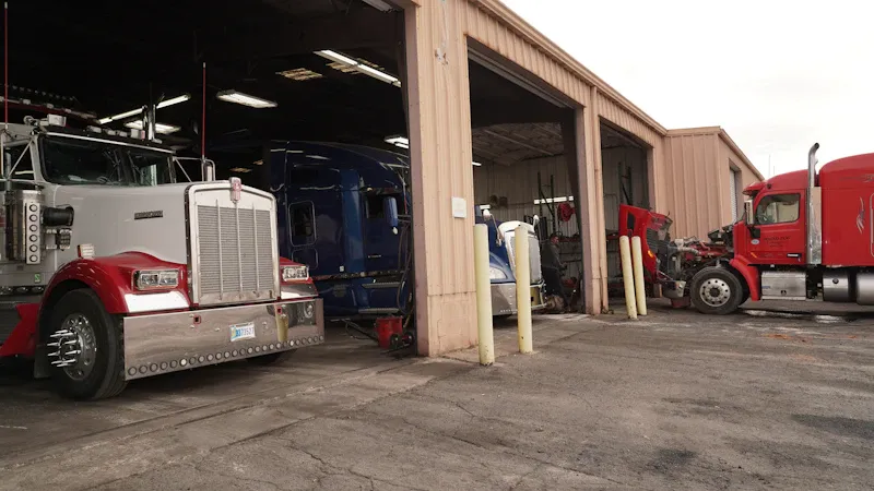 Fleet inspections showing multiple semi trucks parked in active heavy-duty repair bays for maintenance and service.