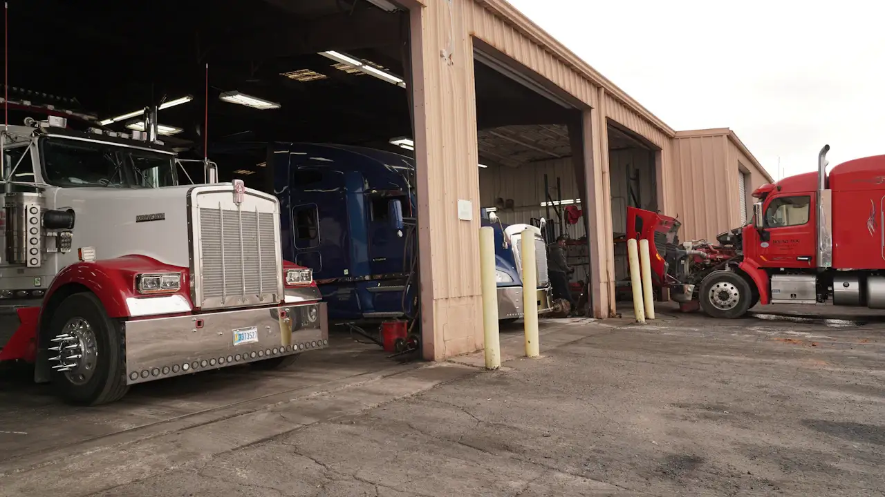 Fleet inspections showing multiple semi trucks parked in active heavy-duty repair bays for maintenance and service.