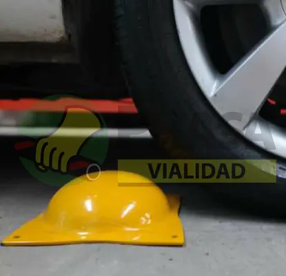 Una boya metálica amarilla junto a la rueda de un vehículo, ilustrando productos de vialidad para señalización efectiva en la carretera.