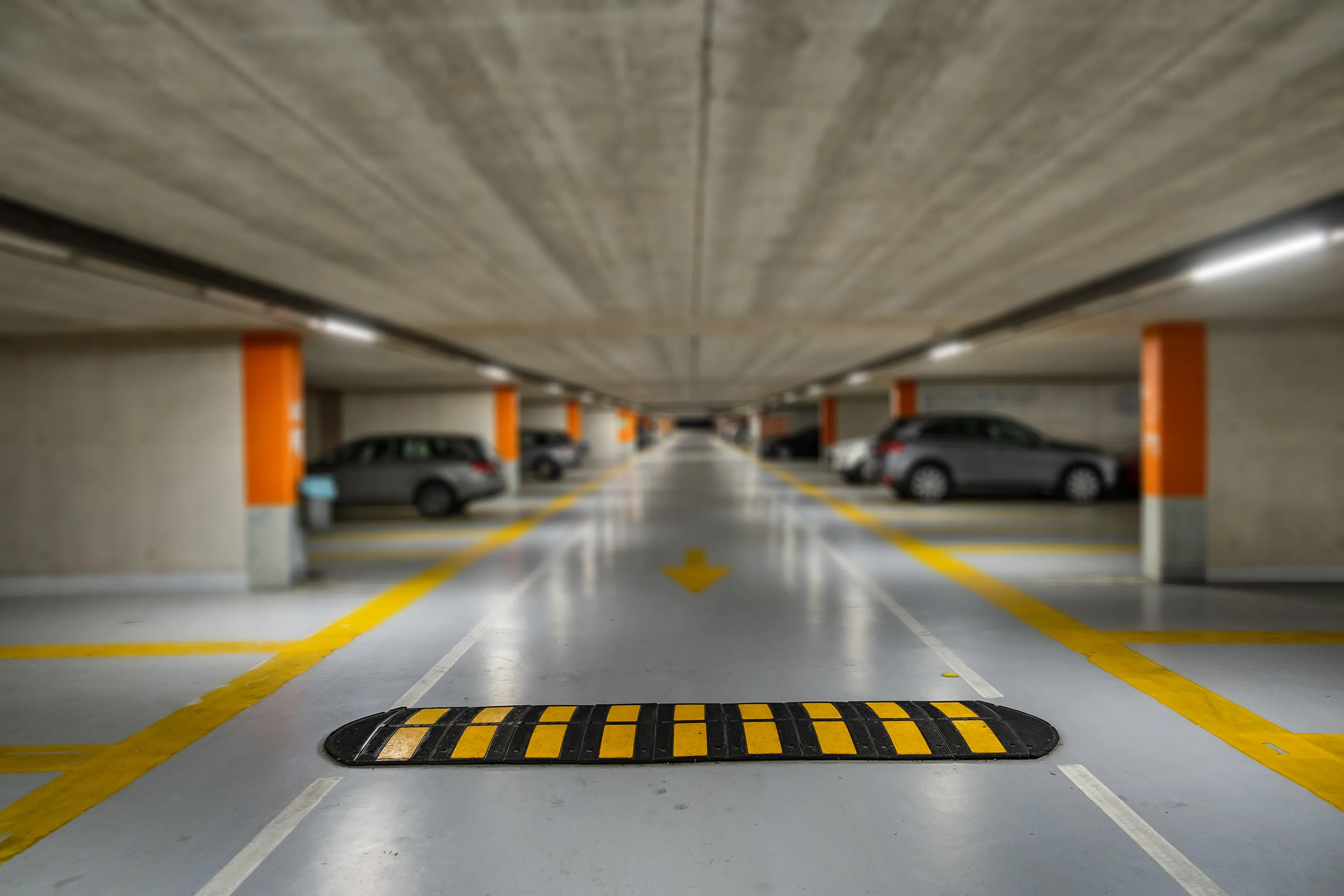 Uno de los tipos de topes viales de Pahasa en un estacionamiento gris, el tope es de color negro con frjanjas amarillas