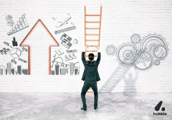 Businessman holding a ladder, preparing to climb towards a large upward arrow on a wall filled with success symbols like money, gears, team, and growth charts.