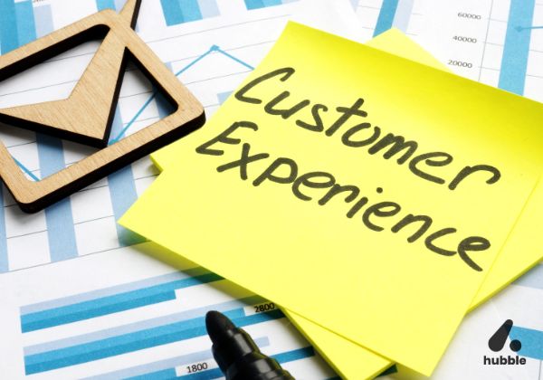 Sticky note with "Customer Experience" written on it, placed over business charts, symbolizing the connection between experience and loyalty.