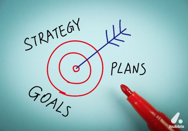 Hand-drawn target with an arrow hitting the bullseye, surrounded by the words "Strategy," "Goals," and "Plans," symbolizing effective co-marketing strategies for channel engagement.
